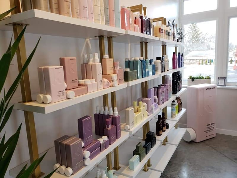 Interior view of AT.hair & co. showing warm white walls and brass fixtures.